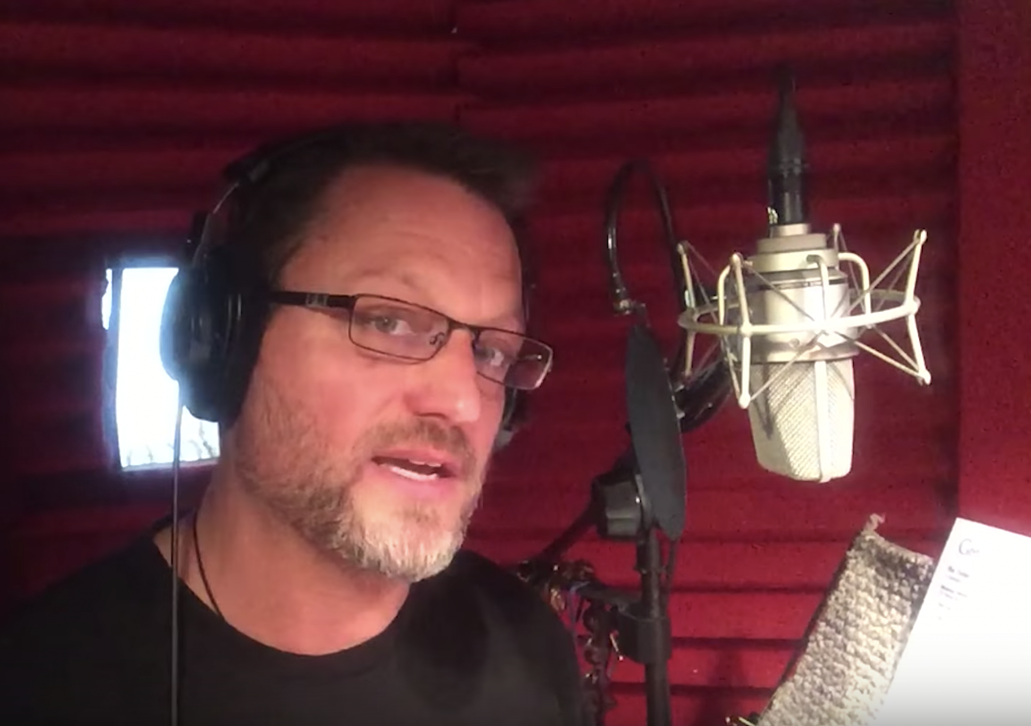 Steve Blum at the microphone with red foam behind