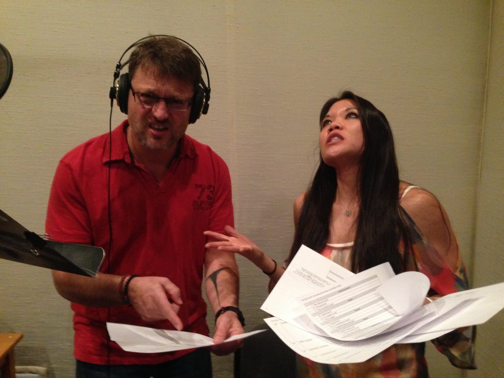 Steve Blum in the studio with another voice actor gesturing to script