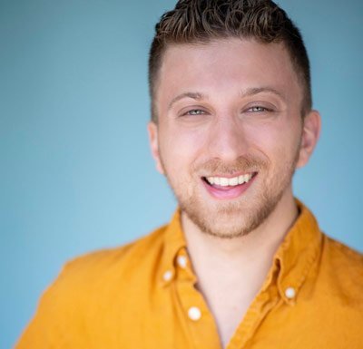 Headshot of Blumvox Studios team member Brandon Blum smiling in a light orange button-up shirt