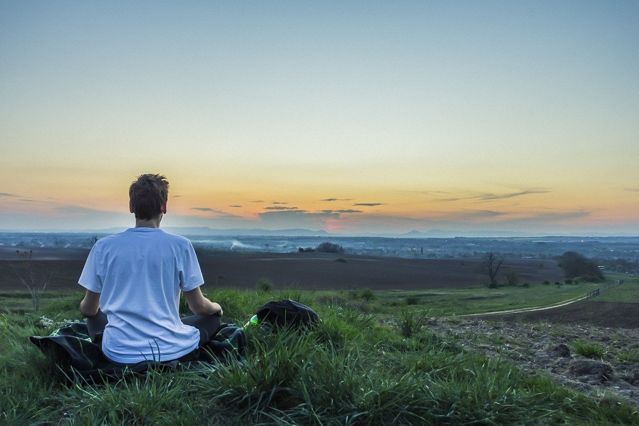 Person recalibrating by meditating in field