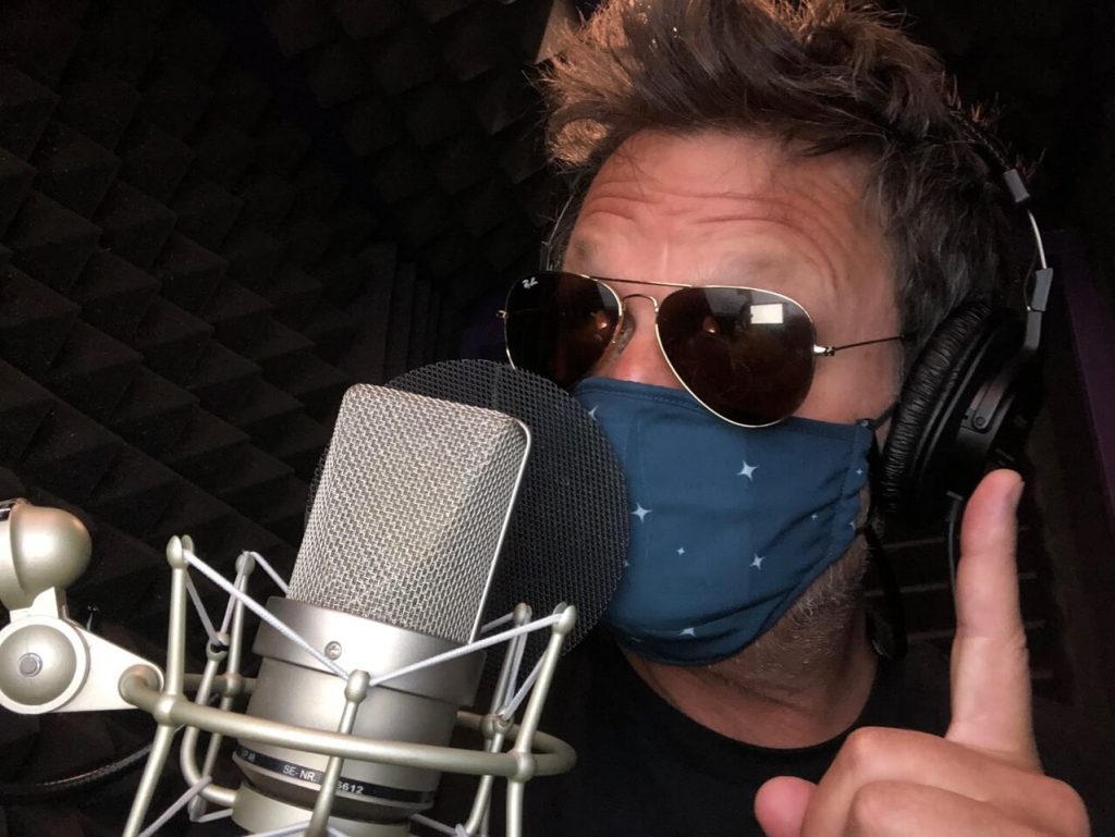 50 Classes-Beyond the Vision_Steve Blum at the mic with sunglasses and a mask on