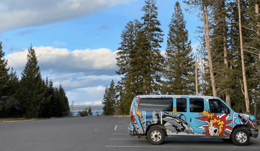 Image of Comic Van parked in parking lot surrounded by forest